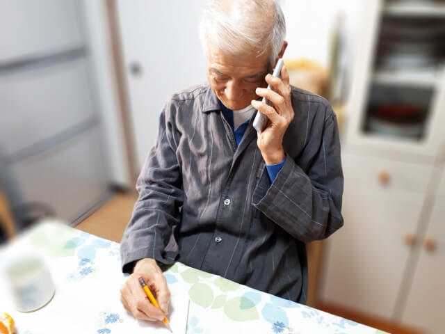 電話で話しながらメモを取る男性