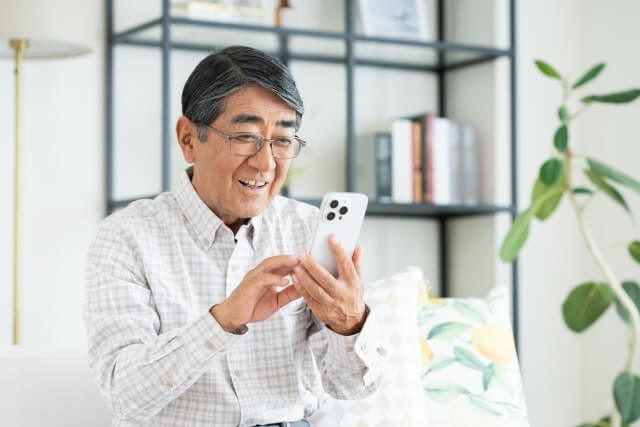 スマホで笑う年配の男性
