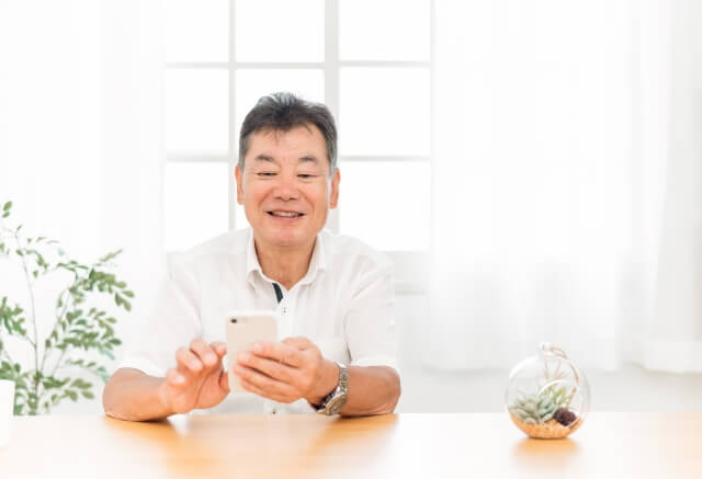 スマホを手に笑顔の年配の男性